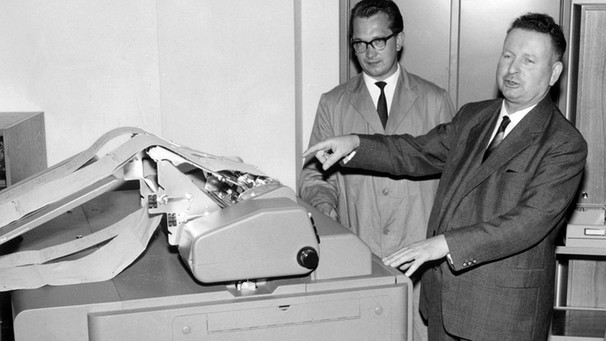 Anton Sabel (re.), der Präsident des Bundesamtes für Arbeitsvermittlung und Arbeitslosenunterstützung, setzt am 8. August 1961 eine neue Rechenmaschine in Gang. | Bild: picture-alliance/dpa