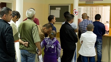 Asylbewerber stehen in einer Schlange an einer Informationsstelle | Bild: picture-alliance/dpa