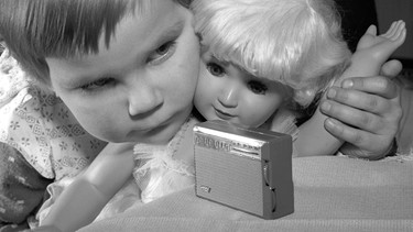 Ein kleines Mädchen betrachtet 1961 den "Solo-Boy" von Grundig, ein kleines Transistorradio das kleiner als eine Schachtel Zigaretten und damit das kleinste Radio seiner Zeit war. | Bild: picture-alliance/dpa