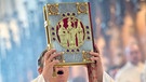Ein Diakon hält während einem Gottesdienst ein Evangeliar hoch | Bild: picture-alliance/dpa
