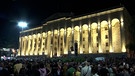 Georgisches Parlament in abendlicher Beleuchtung und mit Demonstrantendavor | Bild: Bayerischer Rundfunk 2024