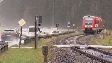 Autos und ein Zug an einem unbeschrankten Bahnübergang | Bild: Bayerischer Rundfunk 2020
