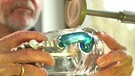 Ein Glasmacher schleift ein neues Gals mit blauem Henkel an der elektrischen Schleifmaschine. | Bild: BR Fernsehen