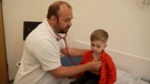 Kinderarzt untersucht einen Jungen | Bild: Bayerischer Rundfunk 2023