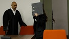 Angeklagte verbirgt ihr Gesicht beim Betreten des Gerichtssals mit einem Aktenordner. Links eben ihr Anwalt Tarig Elobied . | Bild: Bayerischer Rundfunk 2023