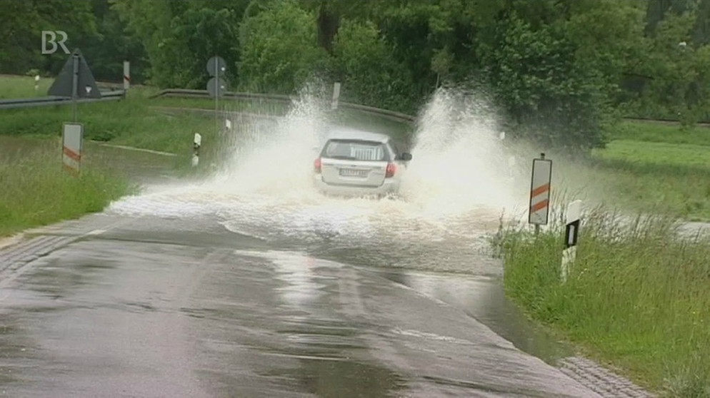 Auto fährt auf überfluteter Straße | Bild: Bayerischer Rundfunk