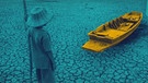 Symbolbild Klimawandel: Eine Person schaut auf einen ausgetrockneten See; das Boot liegt auf Grund. | Bild: BR