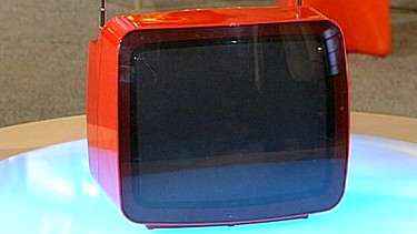 Leuchtend roter tragbarer Fernseher von Grundig, dessen Bedienfläche auf der Rückseite des Gerätes versteckt ist. So erscheint die Front dieses futuristisch anmutenden Fernsehers glatt und elegant. Geschätzter Wert: 50 Euro  | Bild: Bayerischer Rundfunk