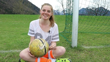 Daniela sitzt neben dem Fußballtor und hält einen Fußball in der Hand | Bild: Bayerischer Rundfunk