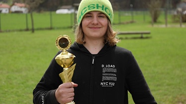 Enzo hält stolz einen Pokal in der Hand | Bild: Bayerischer Rundfunk