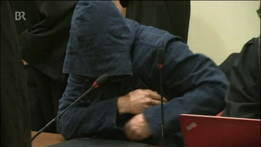 Angeklagter und Kronzeuge hat die Kapuze seiner dunkelblauen Jacke tief ins Gesicht gezogen | Bild: Bayerischer Rundfunk