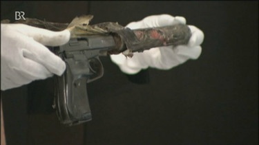 Ein Mann hält eine Ceska-Pistole mit Handschuhen in seinen Händen | Bild: Bayerischer Rundfunk
