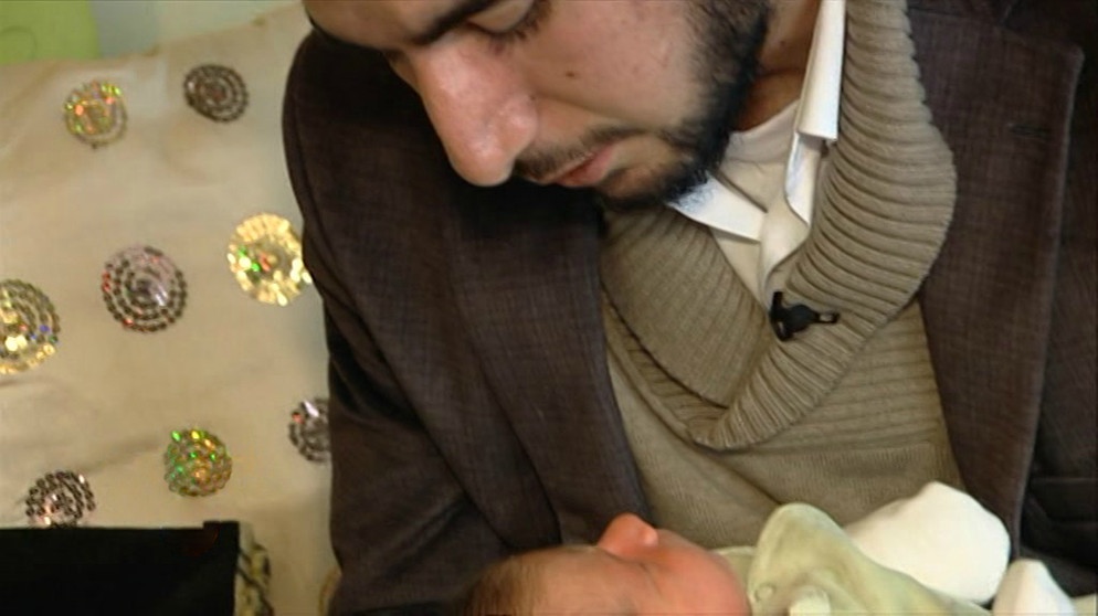 Ein Imam hält ein Baby im Arm | Bild: Bayerischer Rundfunk