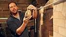 Markus Rusch begutachtet ein Keramikgefäß, das gerade frisch aus dem neuen Holzbrandofen kommt. | Bild: Bayerischer Rundfunk 2023