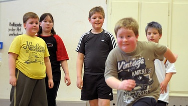 Kinder mit Übergewicht mit hochkonzentrierten Blicken aber offensichtlicher Freude beim Sport in einer Turnhalle. | Bild: picture-alliance/dpa