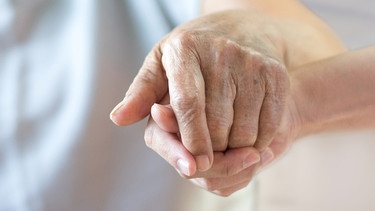 Die Hand einer alten Frau greift in eine junge Hand. | Bild: stock.adobe.com