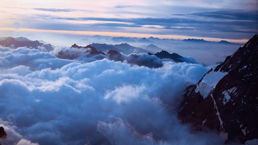 Wolkentyp: Altostratus. Eine mittelhohe Schichtwolke zwischen Berggipfel bei Sonnenaufgang. | Bild: picture-alliance/dpa