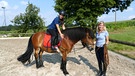 In der ersten Stunde nimmt Reitlehrerin Chrisi Annas Pferd Idefix zur Sicherheit an die Longe. | Bild: BR | Text und Bild Medienproduktion GmbH & Co.KG