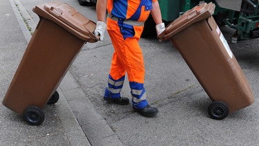 Ein Mitarbeiter der Müllabfuhr holt die braunen Tonnen mit den Bioabfallen ab. | Bild: picture-alliance/dpa
