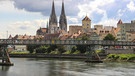 Blick über die Donau auf die Altstadt von Regensburg mit dem Dom St. Peter und dem Goldenen Turm beim Alten Rathaus. Über die Donau führt der Eiserne Steg, eine Brücke für Fußgänger und Radfahrer. | Bild: BR/Guido Fromm