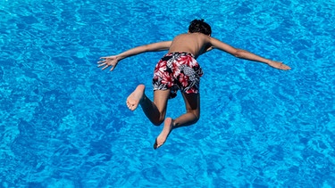 Ein Junge springt im Freibad ins Wasser. | Bild: dpa-Bildfunk/Swen Pförtner