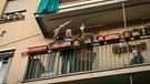 Ein Italiener winkt von seinem Balkon. In der Hand hält er ein Sopran Saxophon. Aufgenommen am 13.03.2020 in Mailand. | Bild: picture alliance / abaca