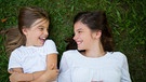 Zwei Mädchen liegen lachend in einer Wiese. | Bild: colourbox.com