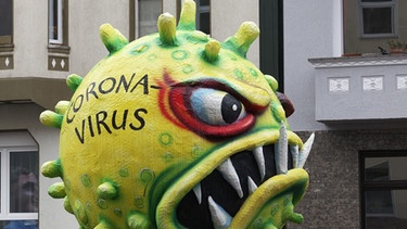 Eine Coronavirus-Figur aus Pappmaschee beim Rosenmontagszug 2020 in Düsseldorf. | Bild: picture alliance/imageBROKER
