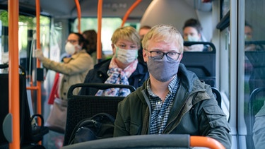 Mehrere Fahrgäste tragen im Bus einen Mundschutz. | Bild: dpa-Bildfunk/Ole Spata