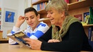Lesepatin Elke Schubert liest in München mit dem 13-jährigen Schüler Nicola Santoro in einem Buch. Elke Schubert, die von der Freiwilligen-Agentur "Tatendrang" vermittelt wird, trifft sich regelmäßig mit Nicola, um mit ihm das Lesen zu üben.  | Bild: picture-alliance/dpa