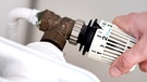 Jemand dreht am Thermostat einer Heizung. | Bild: dpa-Bildfunk/Hauke-Christian Dittrich