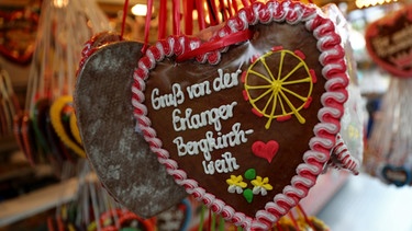 Ein Lebkuchenherz mit der Aufschrift "Gruß von der Erlanger Bergkirchweih" wird auf der Bergkirchweih verkauft.  | Bild: dpa-Bildfunk/Daniel Karmann