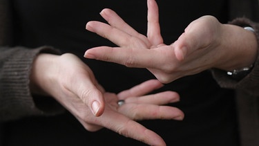 Eine Gebärdendolmetscherin zeigt mit ihren Fingern das Wort "beraten" in Gebärdensprache.  | Bild: dpa-Bildfunk/Arne Dedert