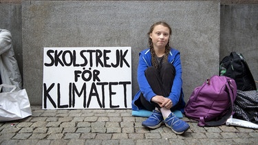 Greta Thunberg vor der Schule mit Transparent auf dem steht: "Skolstrejk för Klimatet" - das heißt übersetzt: "Schulstreik für das Klima". | Bild: picture-alliance/dpa