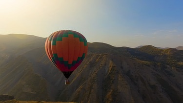 Ein Heißluftballon fährt vor einer Berglandschaft | Bild: colourbox.com