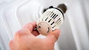 Ein Mann dreht in einer Wohnung am Thermostat einer Heizung. | Bild: dpa-Bildfunk/Hauke-Christian Dittrich