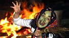 Als Hexe verkleidete Frau mit Besen tanzt in der Walpurgisnacht um das Hexenfeuer. | Bild: picture-alliance/dpa