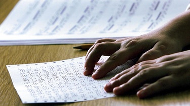 Die Hände einer Korrektorin lesen ein Blatt mit Braillenoten an der Deutschen Zentralbücherei für Blinde zu Leipzig.  | Bild: picture-alliance / ZB | Jürgen Lösel