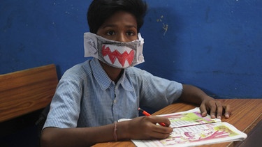 Ein Schüler trägt im Unterricht einen selbst gebastelte Mundschutz, als Maßnahme gegen das Coronavirus. | Bild: dpa-Bildfunk/Mahesh Kumar