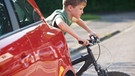 Verkehrsregeln für Fahrradfahrer: Junge schiebt sein Fahrrad zwischen einem parkenden Auto auf die Straße.  | Bild: picture-alliance/dpa
