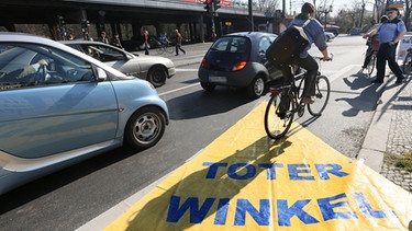 Verkehrsregeln für Fahrradfahrer: Auf der Straße liegt eine große gelbe Plane, die den "Toten Winkel" markiert, den Autofahrer vom Steuer aus nicht einsehen können. | Bild: picture-alliance/dpa