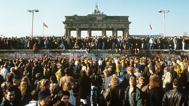 Menschenmenge am 10. November 1989 vor und auf der Berliner Mauer vor dem Brandenburger Tor. Am Tag nach der Öffnung der deutsch-deutschen Grenze in der Nacht vom 09. auf den 10.11.1989  strömten tausende DDR-Bürger nach West-Berlin und in die Bundesrepublik. | Bild: picture-alliance/dpa