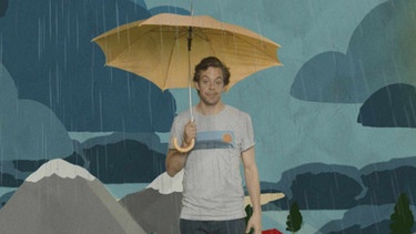 Tobi steht mit einem Regenschirm im Regen. | Bild: Megaherz