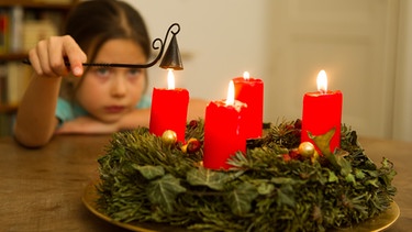 Mädchen löscht die Kerzen an einem Adventskranz. | Bild: picture-alliance/dpa