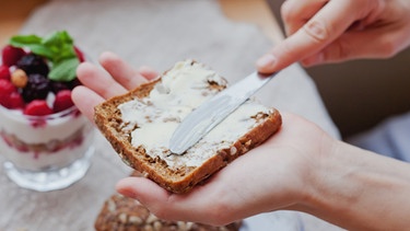 Eine Brotscheibe wird mit Butter bestrichen. | Bild: colourbox.com