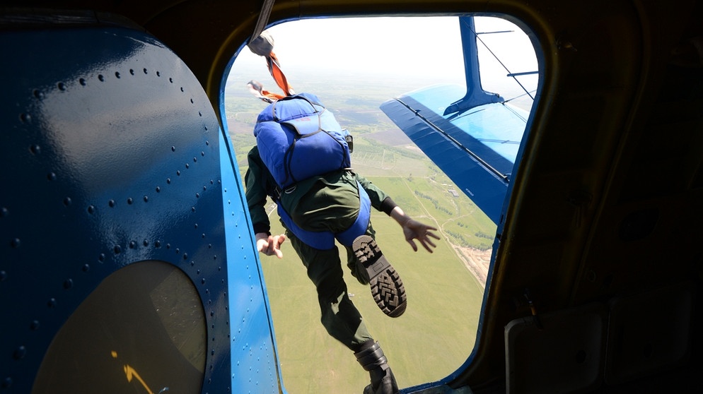 Ein Smoke Jumper - also ein Feuerwehrmann mit Fallschirm - springt aus einem Flugzeug in Russland. | Bild: picture-alliance/dpa