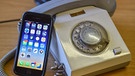 Ein Smartphone vom Typ Apple iPhone6 liegt neben einem Festnetztelefon mit Wählscheibe aus DDR-Zeiten.  | Bild: picture-alliance/dpa
