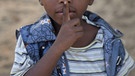 Eine Junge legt den Finger an die Lippen: Eine Geste, die ausdrückt, man soll leise sein. | Bild: picture-alliance/dpa