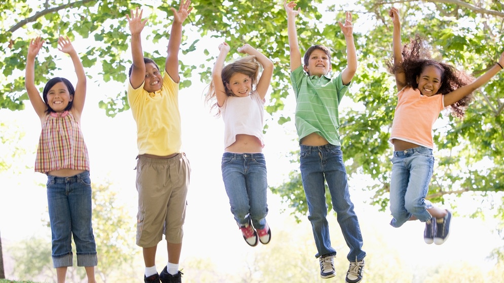 Symbolbild: Kinder springen vergnügt auf einer Wiese in die Luft | Bild: colourbox.com