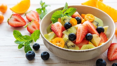 Eine Schüssel mit Obstsalat: Aufgeschnittene Erdbeeren, Kiwis, Heidelbeeren, Orangen und Kumquats. | Bild: colourbox.com
